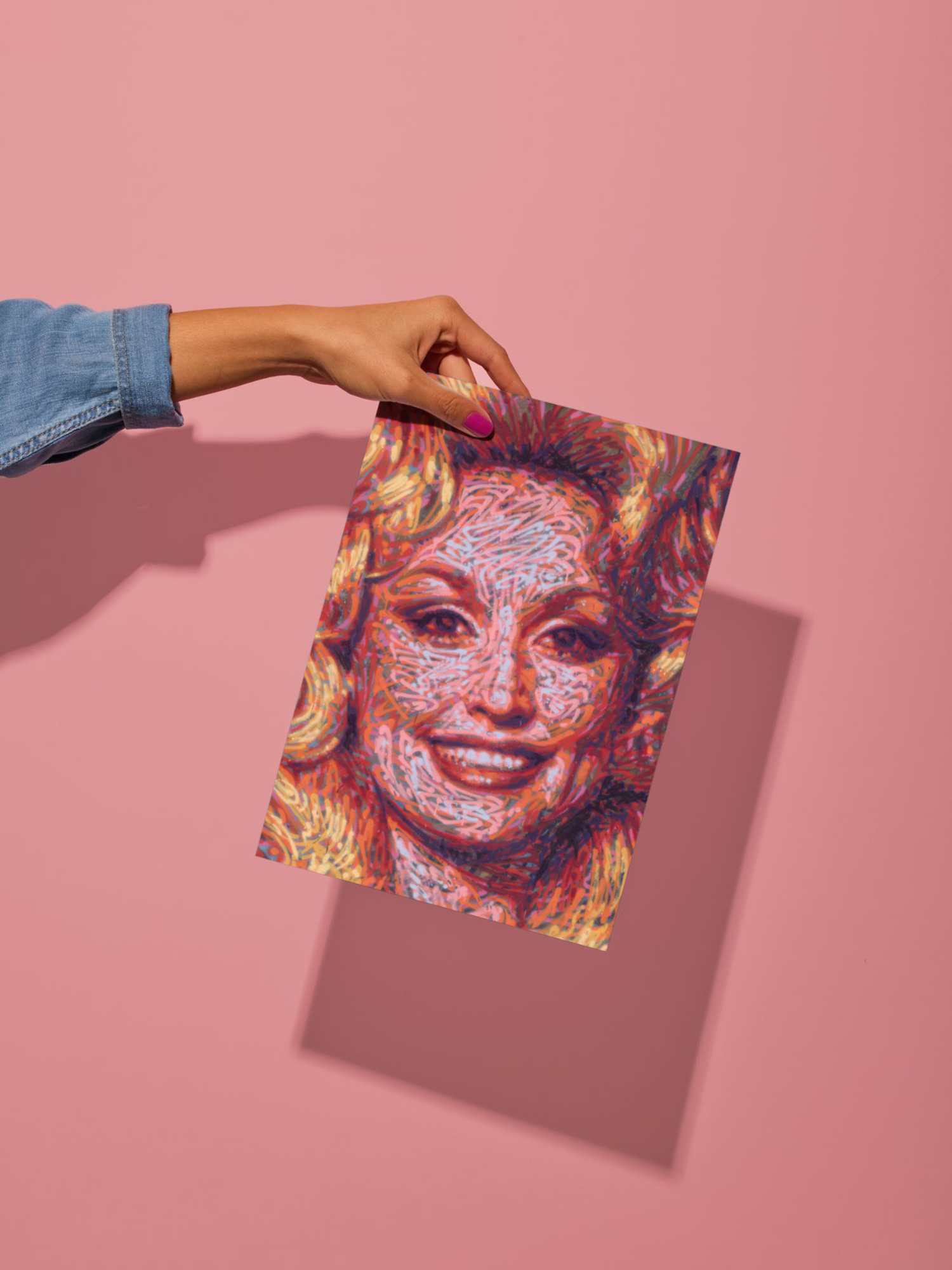 Mockup of a graffiti spray can portrait by Ben Jay of Blank Space Removal of a closeup of Dolly Parton's face and bouffant hair, behind held by a woman's hand in front of a pink wall to show size and shadow.